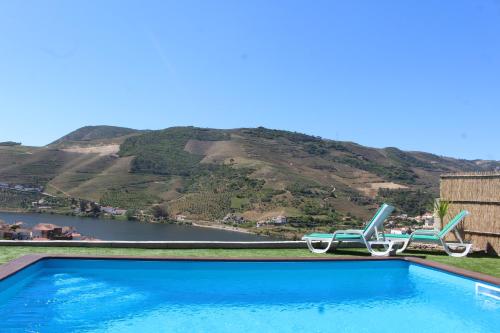 a pool with two chairs and a view of a mountain at Casa José Lourenço in Folgosa