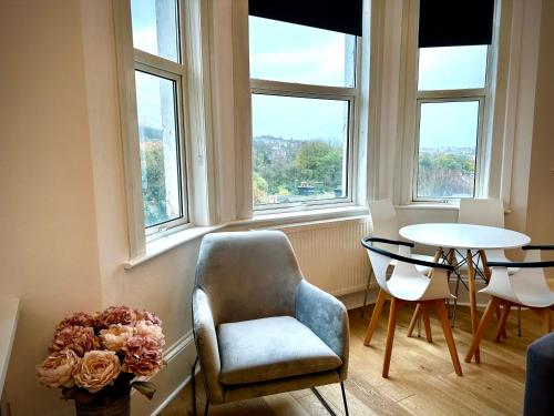 a room with a chair and a table and windows at The Look-out! Park Hills Beach in Hastings