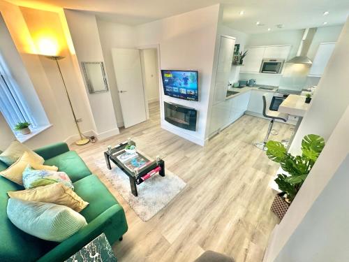 a living room with a green couch and a tv at Coastal Vibes - Stunning Bournemouth Apartment with King Size Bed and Free Parking - Central Location and Close to Beach in Bournemouth