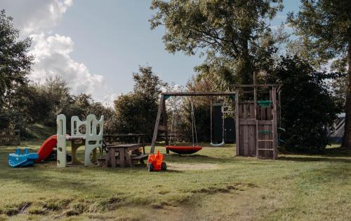 a park with a playground with a swing at Finse Woning op Camping De Tulpenweide in Breezand