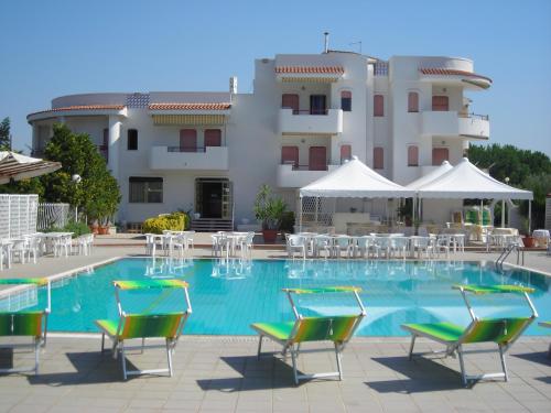 a swimming pool with chairs and a building at Residence Atlante in Leporano