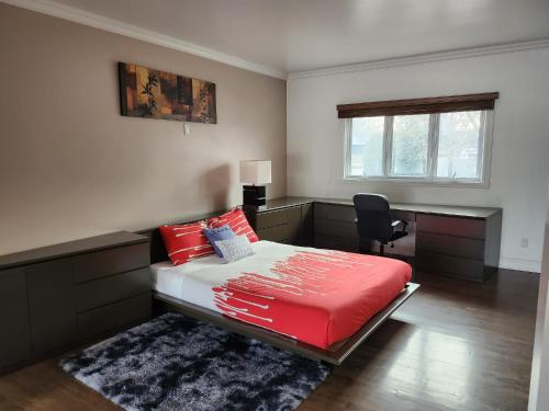 1 dormitorio con cama roja y escritorio en Réveillez-vous, en Repentigny
