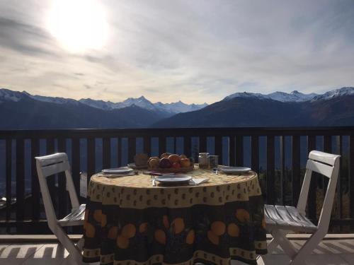 a table with a bowl of fruit on top of a balcony at Crans Montana spacious 80m2 apartment with stunning view & bus stop outside in Crans-Montana