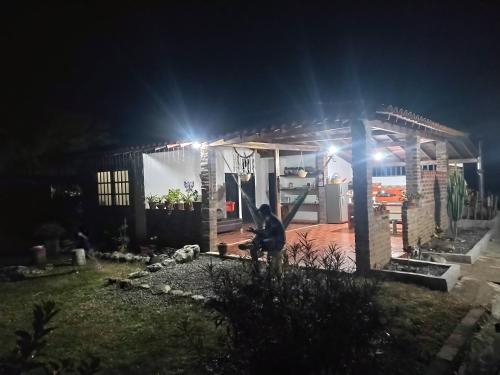 Cabaña el Gaque في كوريتي: شخص يجلس أمام المنزل في الليل