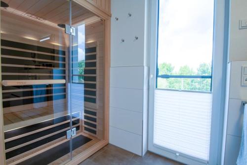 La salle de bains est pourvue d'une douche à l'italienne en verre et d'une fenêtre. dans l'établissement Sielhuus 11 Ferienwohnung mit Dachterrasse und Infrarotsauna und Kamin für bis zu 4 Personen in Fedderwardersiel!, à Fedderwardersiel