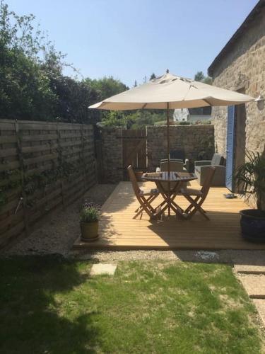 un patio avec un parasol, une table et des chaises dans l'établissement La petite maison bretonne, à Locmariaquer