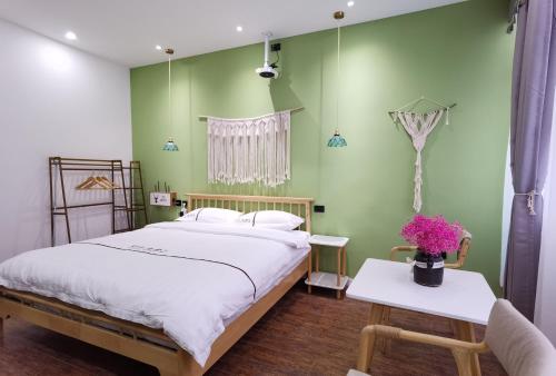 sypialnia z zielonymi ścianami, łóżkiem i stołem w obiekcie Enshi Miaoer One Residence w Enshi