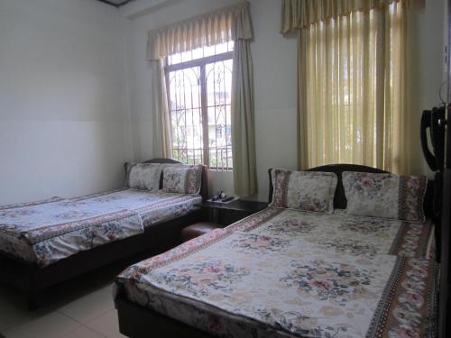 a bedroom with two beds and a window at Nhà Nghỉ Du Lịch Nguyên Vũ in Da Lat