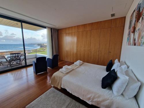 a bedroom with a bed with a view of the ocean at São Vicente Lodge - Panoramic Retreat in Capelas