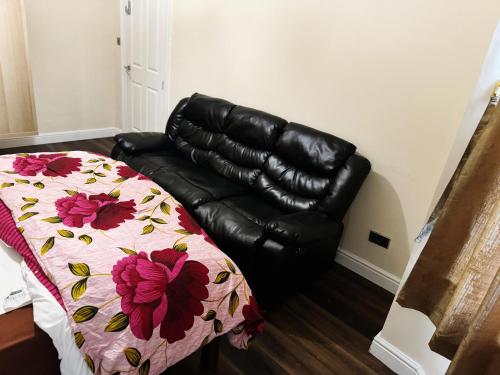 a black leather couch in a room with a bed at Nice and Pleasant in Thornton Heath