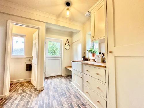 a kitchen with white cabinets and a window at Greenacre Lodge - cosy, dog-friendly rural home with private garden in Redgrave