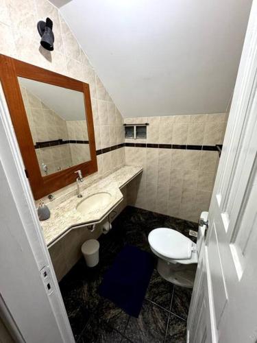 ein Badezimmer mit einem Waschbecken, einem WC und einem Spiegel in der Unterkunft Casa com Piscina ao lado do Shopping in Cabo Frio