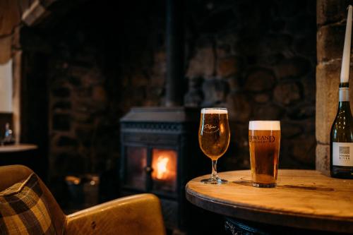 dos vasos de cerveza en una mesa con una botella de vino en The Waddington Arms en Waddington