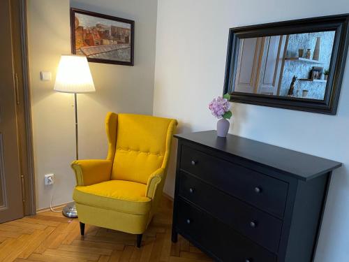 a bedroom with a yellow chair and a dresser at Golden Key Apartments in Liberec