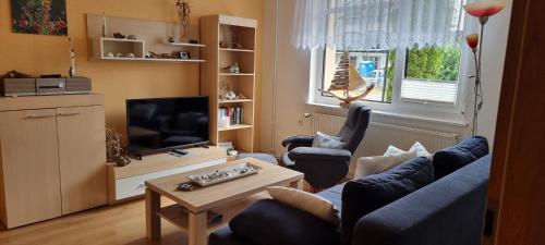 a living room with a blue couch and chairs and a tv at Ferienwohnung Kollwitz in Sassnitz