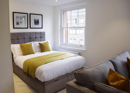 a bedroom with a bed and a window and a couch at Luxury Harley Street Apartments in London