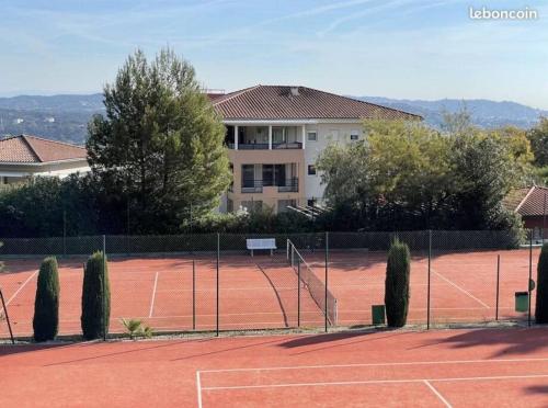 um campo de ténis em frente a um edifício em Appartement piscine/tennis em Mandelieu-la-Napoule