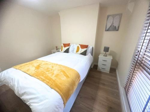 a bedroom with a bed with white sheets and a yellow blanket at Chic 2-Bed Flat Private Garden SE13 in London