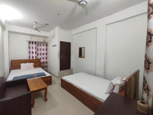 a bedroom with two beds and a table in it at New Hotel Labbaik in Dhaka