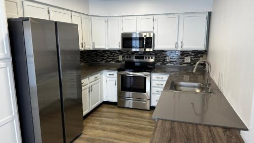 a kitchen with white cabinets and a stainless steel refrigerator at The Copper Hotel - SureStay Collection by Best Western in Camp Verde