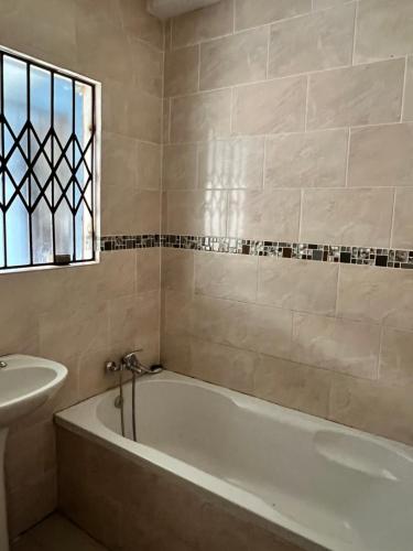 a bathroom with a bath tub and a sink at Luband Guest House 
