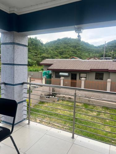 a chair sitting on a balcony looking out at a house at Luband Guest House 