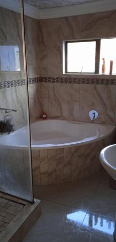 a bathroom with a bath tub and a sink at Luband Guest House 
