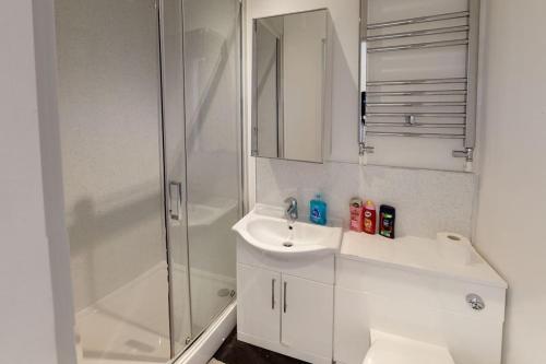 La salle de bains blanche est pourvue d'une douche et d'un lavabo. dans l'établissement Quiet but Central Studio 409, à Nottingham