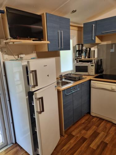 a kitchen with blue cabinets and a white refrigerator at Mobil Home Camping Elysée Vagues Océanes in Le Grau-du-Roi