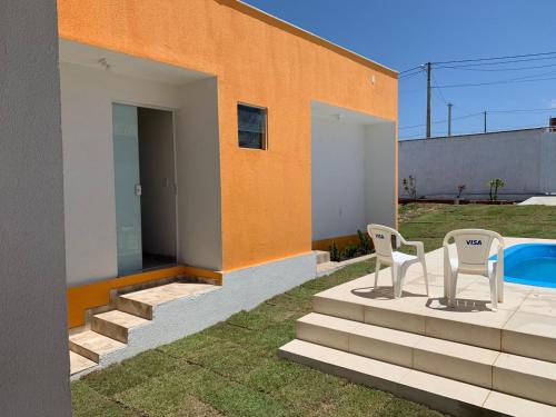 a house with two chairs and a swimming pool at Casa dos Pirineus in Tibau do Sul