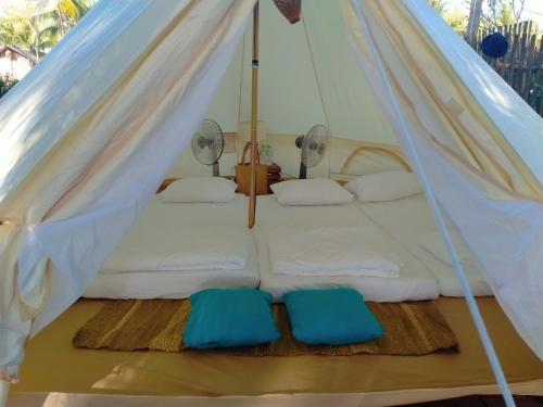 łóżko w namiocie z 2 niebieskimi poduszkami w obiekcie Hola Beach - Beach Club & Eco Glamping Resort w mieście Ke Ga