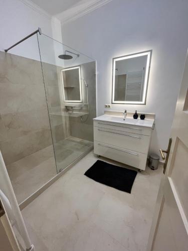 ein weißes Bad mit einer Dusche und einem Waschbecken in der Unterkunft Ady1 Apartment in Kaposvár