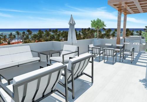 une terrasse avec des chaises, des tables et un parasol dans l'établissement Maple Beach by DR Collection, à Punta Cana