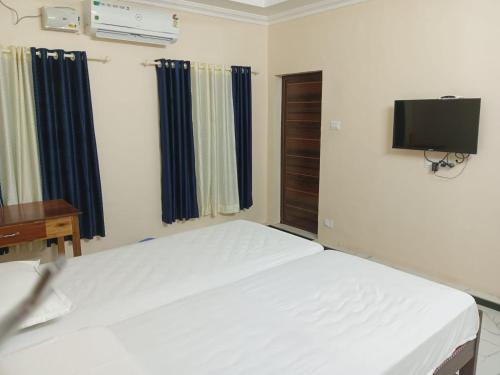 a bedroom with a bed and a tv on the wall at SRI PADMANABHA TOURIST HOME in Chacka