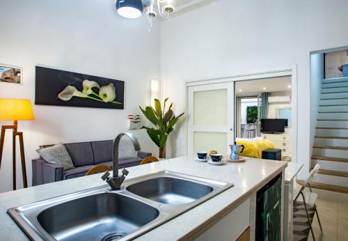 a kitchen with a sink and a living room at Casa Orchidea - The Fab Stay in Brindisi