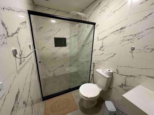 a bathroom with a toilet and a glass shower at Apartamento Loft 07 em Cabo Frio in Cabo Frio