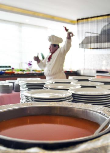 a chef standing in a kitchen with a pot of soup at Belkon Hotel in Belek