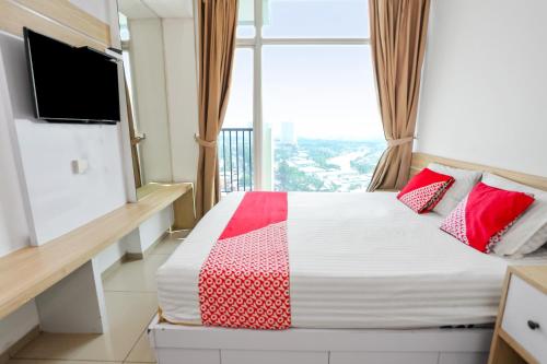 um quarto com uma cama com almofadas vermelhas e uma janela em OYO 93432 Tree Room Hotel em Kebonnanas