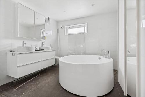 a white bathroom with a tub and two sinks at Fantastisk utsikt, nært sentrum in Tromsø