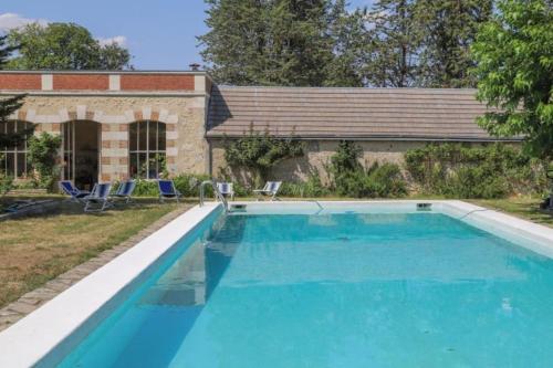 une piscine avec deux chaises et une maison dans l'établissement Château dans le Val de Loire, à Coulanges