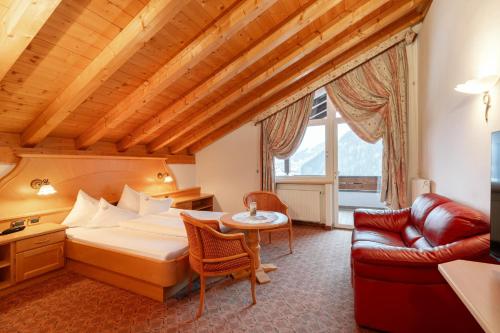 ein Hotelzimmer mit einem Bett und einem Sofa in der Unterkunft Piccolo Hotel in Wolkenstein in Gröden