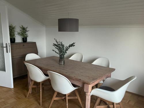 a dining room with a wooden table and white chairs at Helle, ruhige Ferienwohnung mit Balkon in Bad Tölz