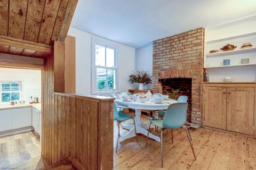 a dining room with a table and a brick fireplace at Henley Street Townhouse in Oxford
