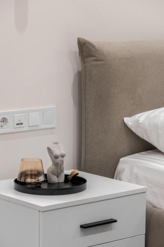 a white bedside table with a statue on it next to a bed at FORUM apart in Lviv