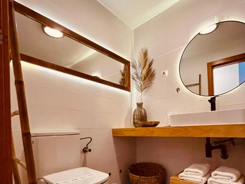 a bathroom with a toilet and a mirror at epicenter SANTACRUZ in Lagoa