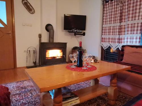 een woonkamer met een tafel met wijnglazen en een open haard bij Vikendica Cican Jahorina in Jahorina