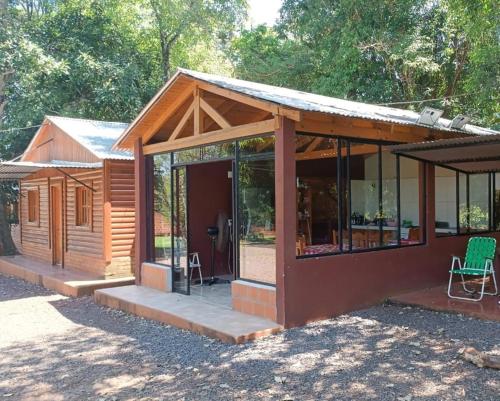 a wooden cabin with glass windows and a patio at Cabañas El Despertar in Puerto Iguazú