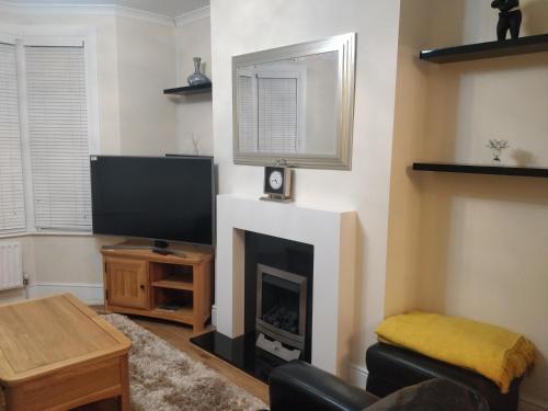 a living room with a fireplace and a flat screen tv at Whites Place in Slades Green