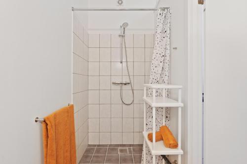 y baño con ducha y toallas de color naranja. en Come Stay - Charming Oasis in The Heart of Aalborg, en Aalborg