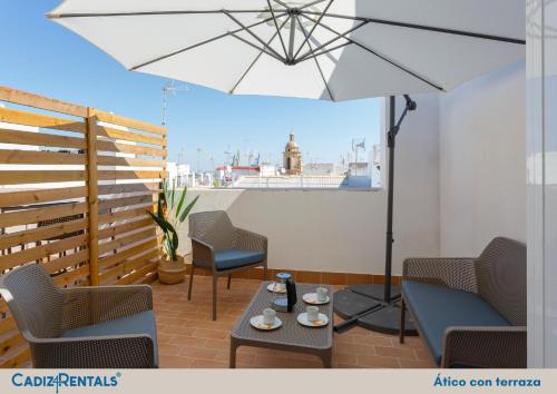 a patio with chairs and a table and an umbrella at Apartamentos La BRUJULA by CadizRentals in Cádiz